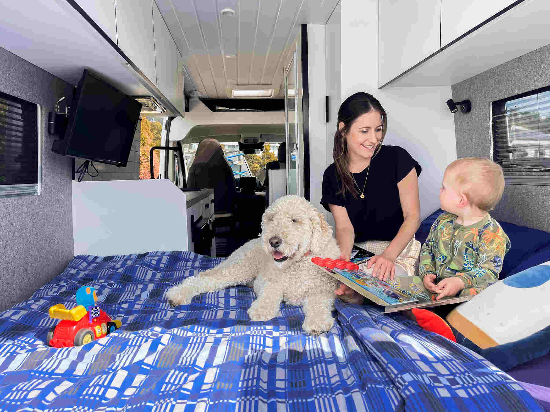 Mom reading book to a child with a dog sitting on bed